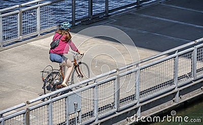 Girl in shorts rides a bicycle on a floating dock on the Willamette River, preferring an active healthy lifestyle Editorial Stock Photo