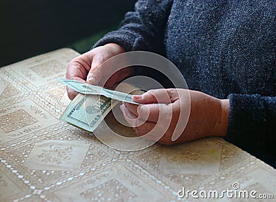 Slender purse. Old woman holding dollar cash money in hands at home Stock Photo