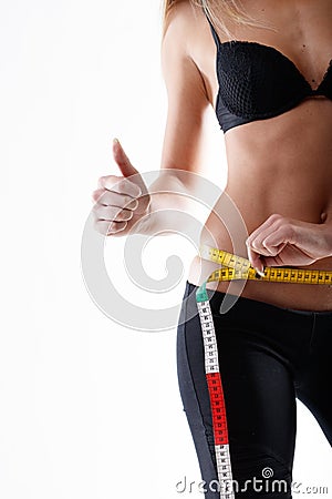 Slender young woman measuring her hips giving a thumbs up Stock Photo