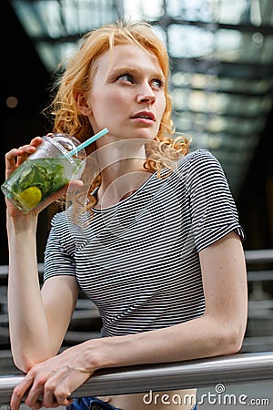 Slender young woman in striped shirt drinking refreshing mojito Stock Photo