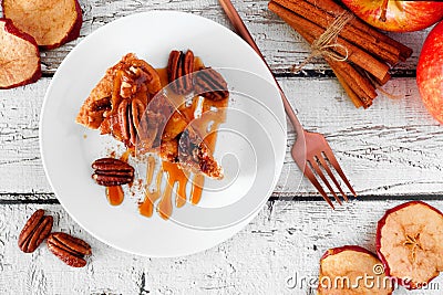 Slice of autumn caramel apple pecan cheesecake, top view table scene over white wood Stock Photo