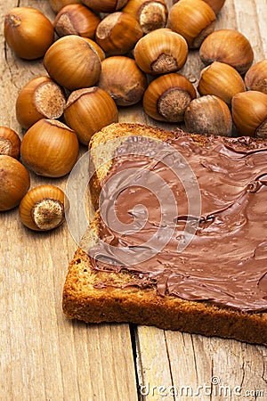 Slice of bread with chocolate with hazelnuts on wood Stock Photo