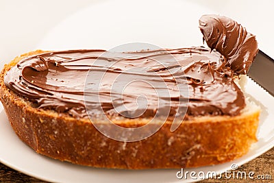 Slice of bread with sweet chocolate nougat spread on wooden back Stock Photo