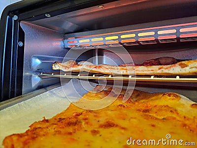 Slice of cheese pizza close-up real life in the kitchen, reheat in the electric oven Stock Photo