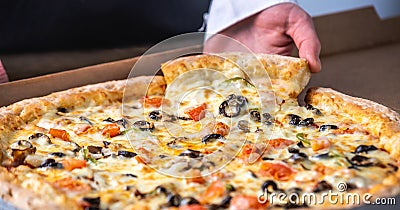 Slice of fresh hot vegetarian pizza with a stretch of mozzarella cheese in the cook`s hand Stock Photo