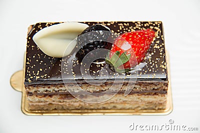 Slice of layered chocolate cake topped with a strawberry and bl Stock Photo