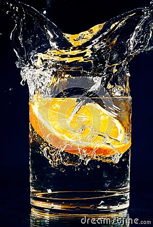 Slice of orange falling down in glass with water Stock Photo