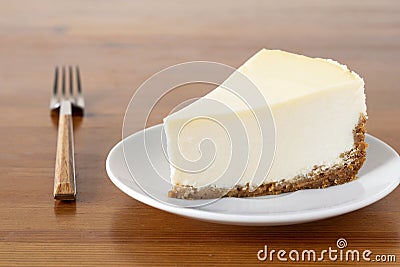 Slice of plain New York Cheesecake on wooden table Stock Photo