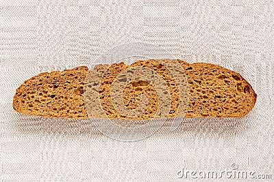 Slice of rye bread with an appetizing crispy brown crust on a gray linen tablecloth. Tasty, usefull and nutritious Stock Photo