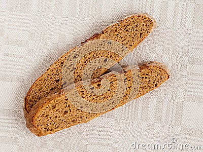 Slice of rye bread with an appetizing crispy brown crust on a gray linen tablecloth. Tasty, usefull and nutritious. Stock Photo