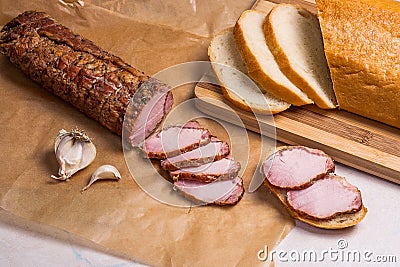 Slice smoked meat or ham, garlic and white wheat bread on brown Stock Photo