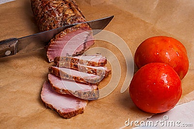 Slice smoked meat or ham, knife and two tomatoes on brown packing paper.. Stock Photo