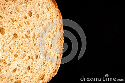 slice of white bread close up isolated on a black background. rough dappled textured surface chopped piece loaf of natural organic Stock Photo