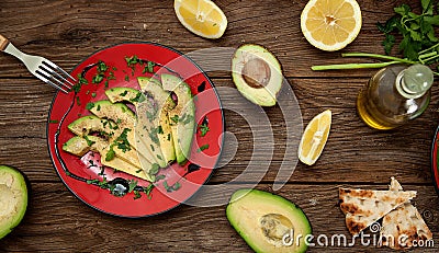 Sliced avocado on a red plate on a a rustical wooden table Stock Photo