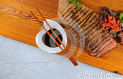 Sliced medium rare grilled beef with soy sauce on cutting board Stock Photo