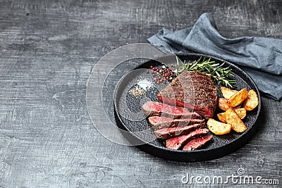 Sliced medium rare grilled beef steak and potato wedges Stock Photo