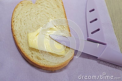 Sliced bread spread with butter or margarine and a knife Stock Photo