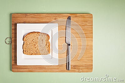 Sliced brown bread on square white plate with knife Stock Photo