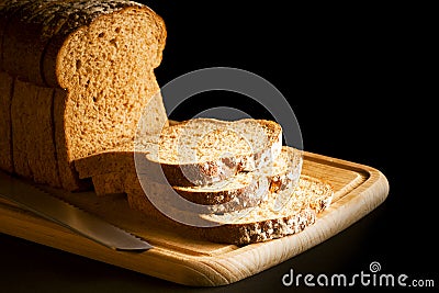 Sliced brown bread on wooden chopping board Stock Photo