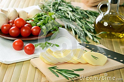 Sliced cheese, tomatoes and herbs on a kitchen table Stock Photo