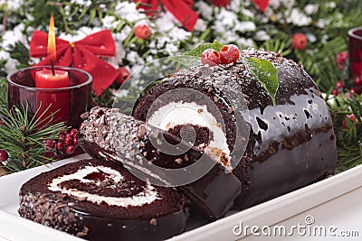 Sliced Christmas yule log cake on plate with candle Stock Photo
