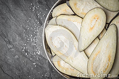 Sliced eggplants with salt in the metal plate on the stone table top view Stock Photo