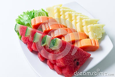 Sliced fruits for health mixed with watermelon, papaya, pineapple with vegetable and lime on white dish and white table background Stock Photo