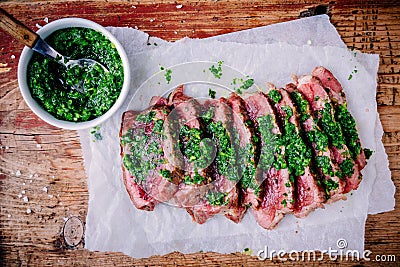 Sliced grilled barbecue beef steak with green chimichurri sauce Stock Photo