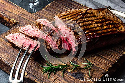 Sliced grilled medium rare beef steak served on wooden board Barbecue, bbq meat beef tenderloin. Top view, slate Stock Photo