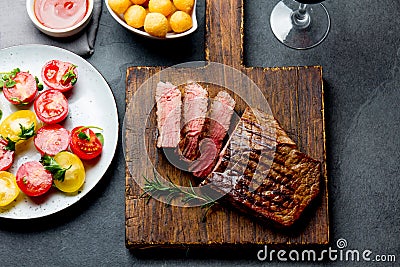 Sliced grilled medium rare beef steak served on wooden board Barbecue, bbq meat beef tenderloin. Top view, slate background Stock Photo