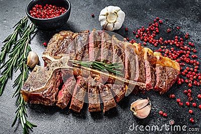 Sliced Grilled T-bone steak. Cooked tbone beef meat. Black background. Top view Stock Photo
