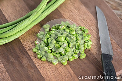 Sliced with a knife, raw long bean on wood cutting board. Stock Photo