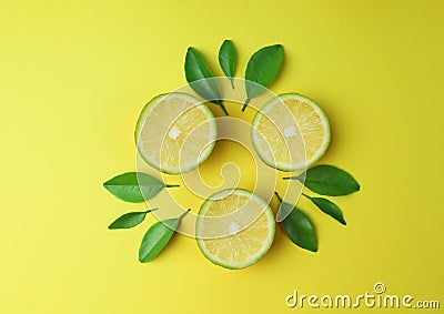 Sliced lime lemon with green leaf on yellow background Stock Photo