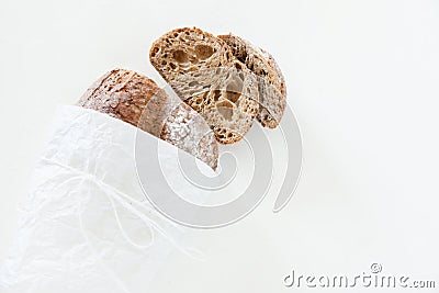 Sliced loaf of homemade bread in a paper on a white background w Stock Photo