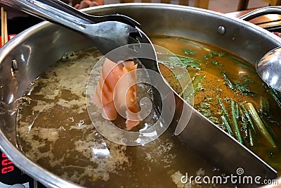 Sliced Meat is being dipped in the hot boiling black soup at shabu store Stock Photo