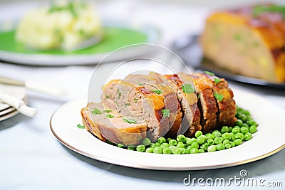 sliced meatloaf on a plate with green peas and mashed potatoes Stock Photo