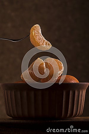 Sliced naartjie being lifted out of a bowl Stock Photo