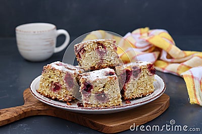 Sliced oatmeal pie with cherry sprinkled with powdered sugar on a plate on a dark background Stock Photo