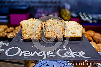 Sliced orange breads on black board and Orange cake hand-sketched typographic element on chalkboard background.Bakery label. Stock Photo