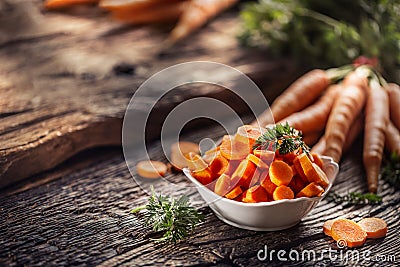 Sliced pieces of carrot in a bowl and a fresh bunch of carrots in the background Stock Photo