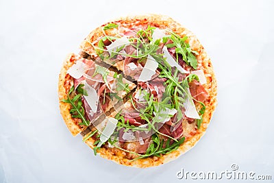 Sliced pizza with prosciutto parma ham, arugula (salad rocket) and parmesan on white background top view Stock Photo