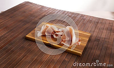 sliced prosciutto on a wooden board on empty table. pork ham on a brown background. composition meat delicacy. Stock Photo