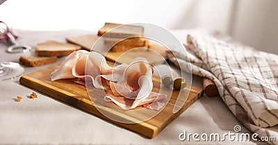 sliced prosciutto on a wooden board. pork ham on a light background. composition meat delicacy with olives and bread. Stock Photo