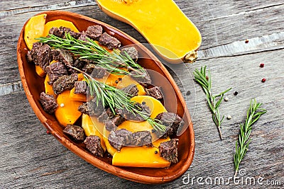 Sliced pumpkin baked with meat in a clay pot. Autumn meal with rosemary and spices Stock Photo