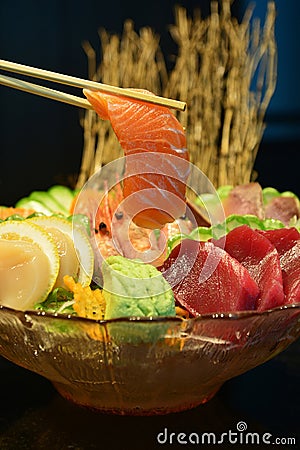 Sliced raw salmon with chopsticks holding it Stock Photo