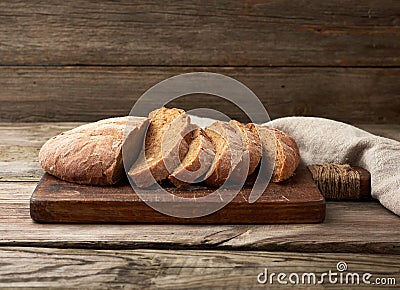 Sliced round baked rye flour bread on a wooden cutting board Stock Photo