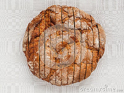 Sliced round loaf of rye bread with an appetizing crispy brown crust on a gray linen tablecloth. Tasty, usefull and nutritious. Stock Photo