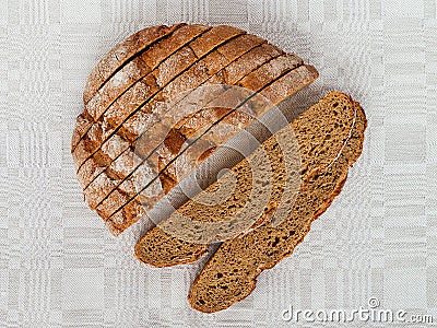 Sliced round loaf of rye bread with an appetizing crispy brown crust on a gray linen tablecloth. Tasty, usefull and nutritious. Stock Photo