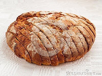 Sliced round loaf of rye bread with an appetizing crispy brown crust on a gray linen tablecloth. Tasty, usefull and nutritious. Stock Photo