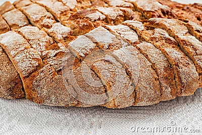 Sliced round loaf of rye bread with an appetizing crispy brown crust on a gray linen tablecloth. Tasty, usefull and nutritious. Stock Photo